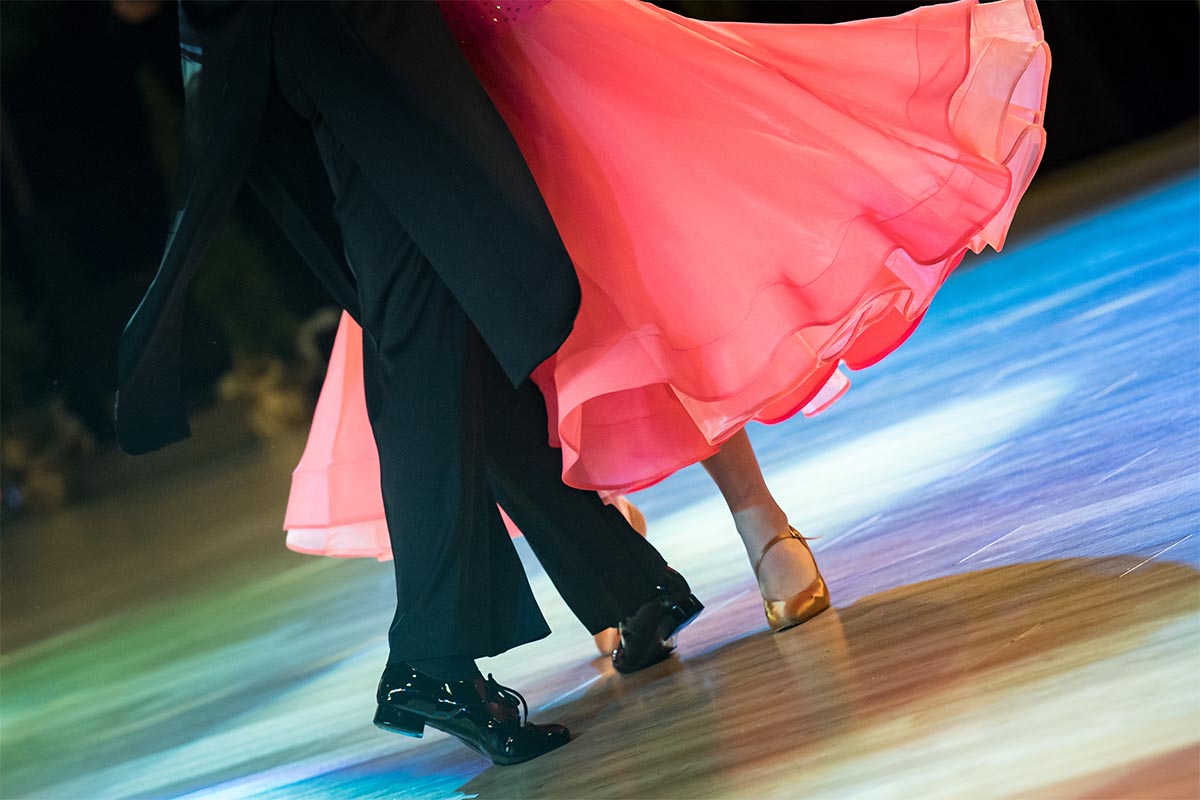 Coppia di ballerini da sala che esegue passo di danza su pavimento danza con luci e atmosfera di gara